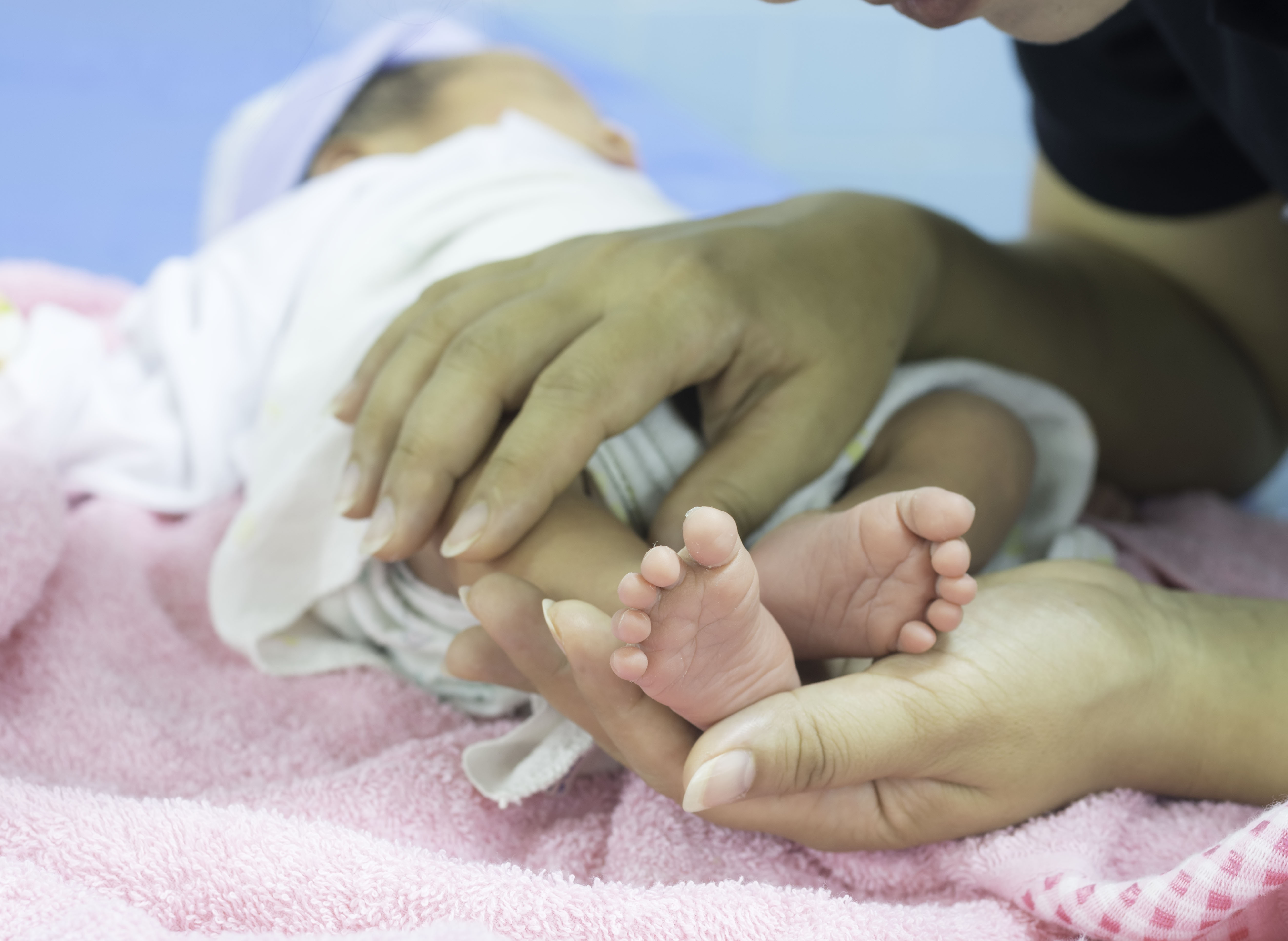 The,Woman,Is,Holding,The,Feet,Newborn,Baby,Sleeping,On